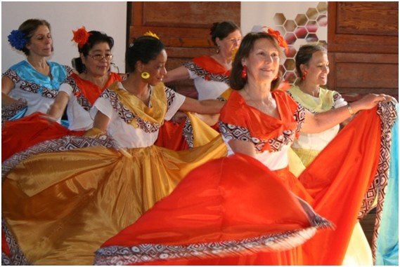 Several women dancing wearing long bright skirts